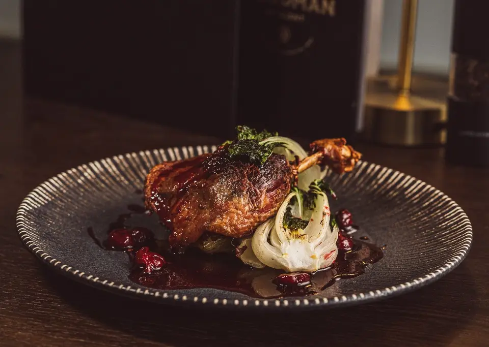 Plated duck leg dish on a dark table